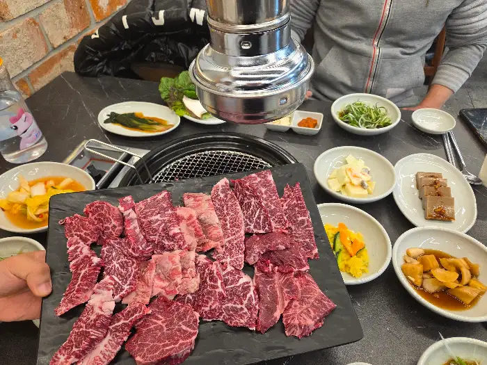 테이블 위에 놓인 다양한 칡소 부위와 곁들임 찬, 소스