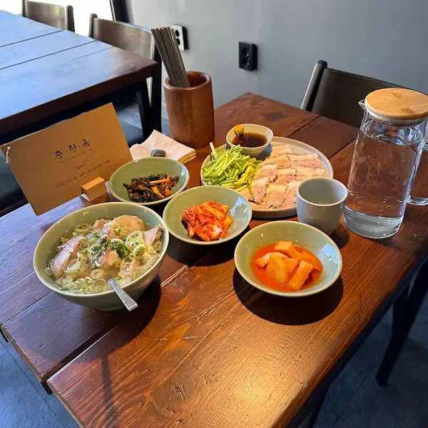 푸짐하게 차려진 식탁 위에서 돼지국밥과 수육, 반찬들을 항공샷으로 담은 모습