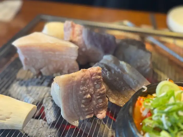 숯불 위에서 암퇘지 고기가 맛있게 익어가고 있다. 붉은 숯불이 고기에 은은한 열을 가하고 있다.