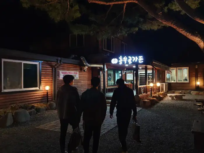 저녁 어스름 속 돼지갈비집 외관, 조명이 켜져 따뜻한 분위기를 자아냅니다.