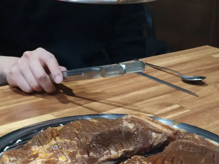 무쇠 불판 위에 올려진 두툼한 돼지갈비. 숯불 위에 올려져 익어가는 모습이 먹음직스럽습니다.