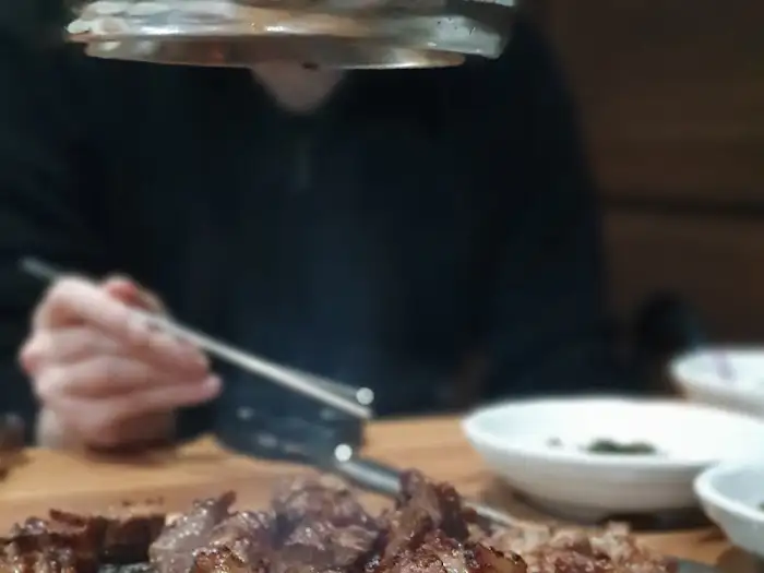 잘 구워진 돼지갈비를 집게와 가위로 자르고 있는 모습. 고기가 촉촉해 보입니다.