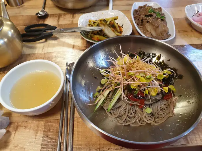 오리 누룽지 백숙이 담긴 놋그릇과 곁들임 반찬