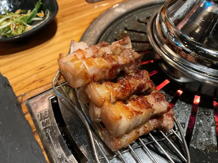 잘 익은 오겹살 조각들이 식힘망에 담겨 있는 모습