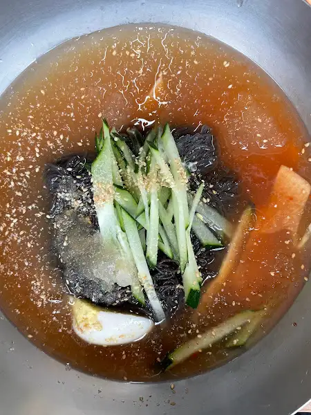 시원한 육수 위로 오이와 계란 지단이 얹어진 물냉면