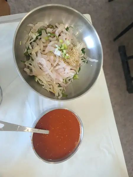 다양한 해산물과 채소가 어우러진 비빔밥 재료와 빨간 양념장