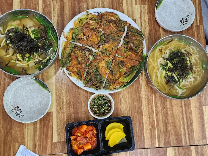 테이블에 차려진 다양한 음식들 - 칼국수, 쌀국수, 파전, 반찬 등