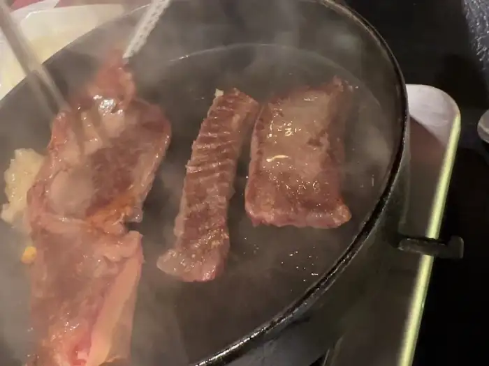 집게로 팬에서 고기를 뒤집는 모습