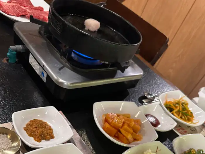점화된 휴대용 버너와 팬, 그리고 곁들임 반찬들