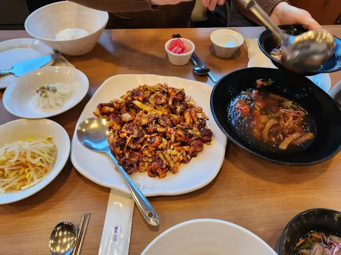 여러 가지 음식이 차려진 테이블 전체 모습, 쭈꾸미 볶음과 피자, 밥 등이 보인다.