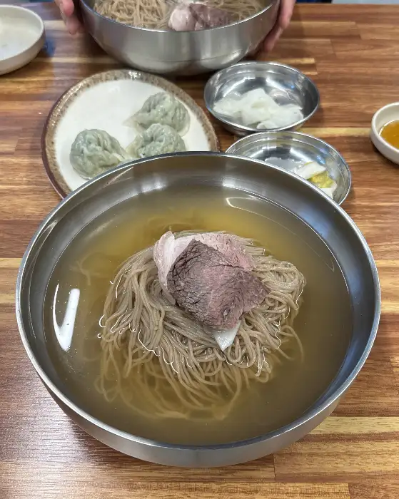 여러 개의 평양냉면과 만두가 담긴 상차림