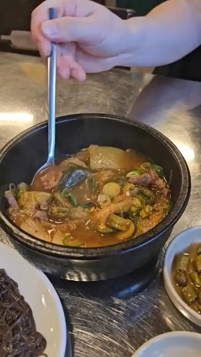 뜨거운 해장국을 덜어내는 모습. 건더기와 국물이 푸짐하게 담겨 있다.