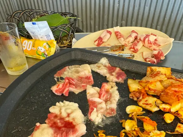 불판 위에서 익어가고 있는 삼겹살, 김치, 마늘