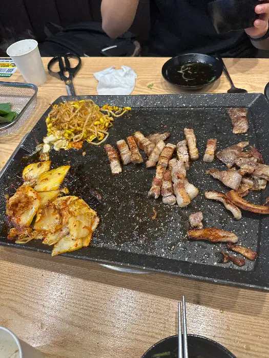 잘 구워진 고기와 김치, 콩나물이 함께 올려진 불판