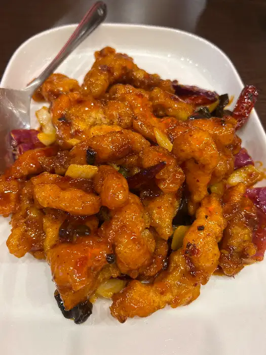 탕수육 조각들이 접시에 담겨 있고, 그 위에 달콤한 소스가 뿌려져 있다.