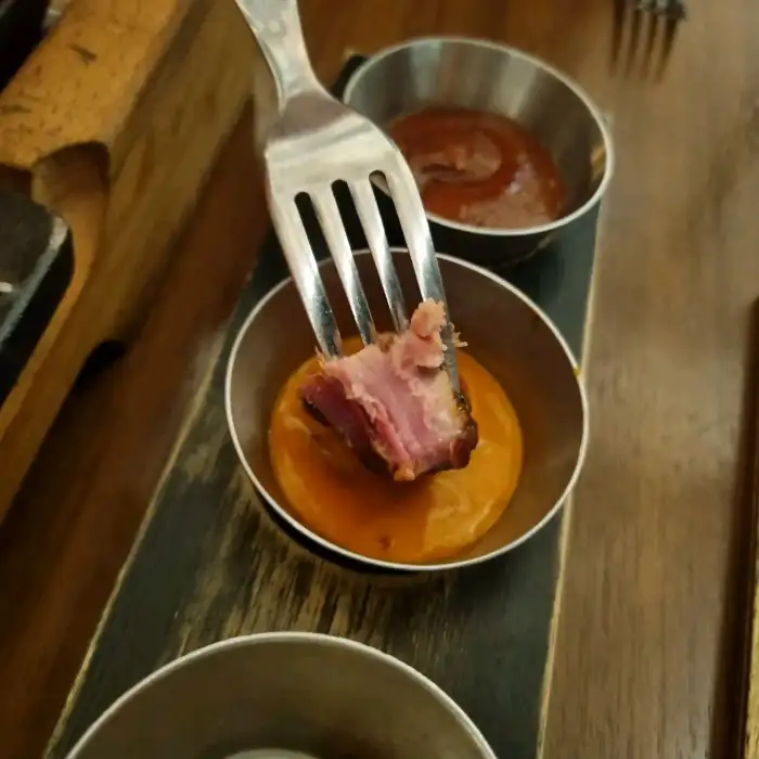 포크에 찍힌 고기 조각을 소스에 찍는 모습.
