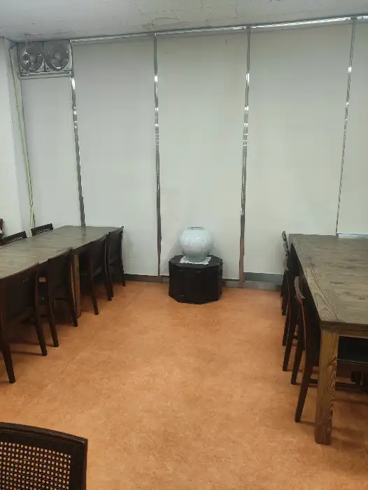 테이블 세팅 모습. 여러 개의 테이블과 의자가 가지런히 놓여 있으며, 중앙에는 큰 항아리가 놓여 있습니다.