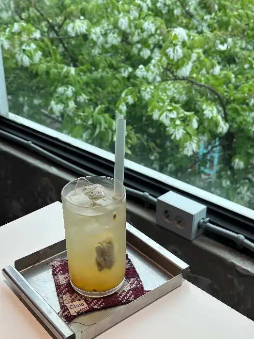 창가에 놓인 음료와 푸른 나무 풍경