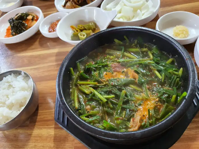 따뜻한 밥과 흑염소 전골이 함께 담긴 밥상. 밥공기에는 윤기 나는 쌀밥이 가득 담겨 있고, 전골 냄비 안에는 국물과 건더기가 먹음직스럽게 보인다.