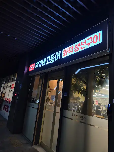 저녁 불빛 아래 박가네 고등어 화덕 생선구이 간판