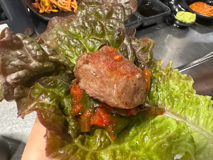 신선한 상추 위에 고기와 쌈장을 올려 한 쌈을 쌌습니다.