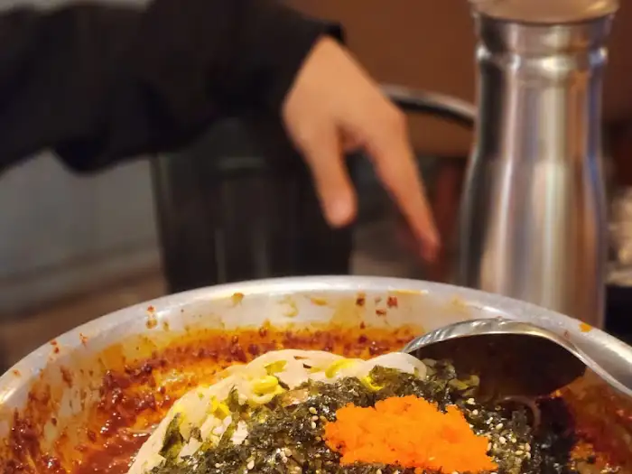 흰 밥 위에 얹어진 찜 재료와 날치알
