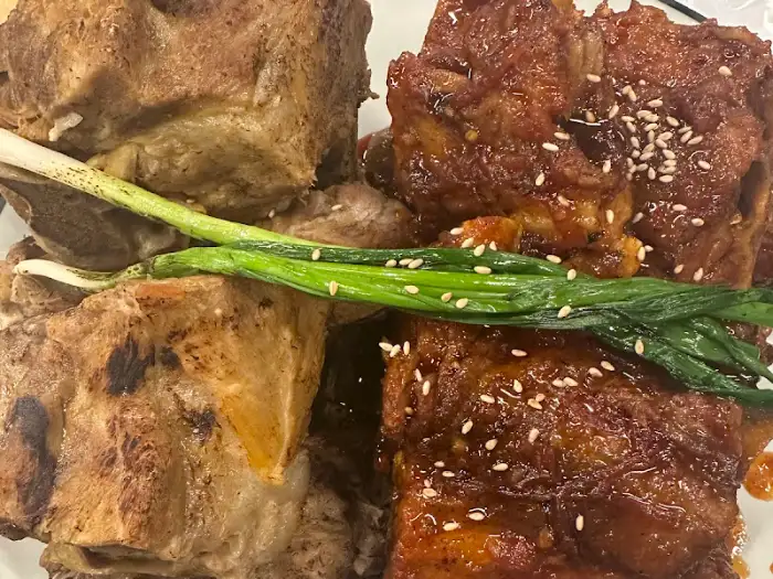 양념 뼈구이와 소금구이가 섞여 있으며, 그 위에 파채가 올려져 있습니다. 뼈구이 사이로 얇고 긴 파가 보입니다.