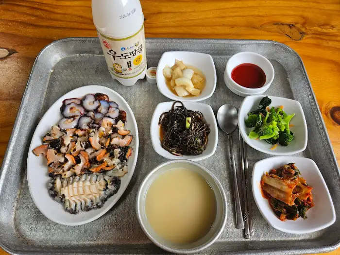 해산물 모듬, 반찬, 국물, 막걸리 등이 차려진 식탁