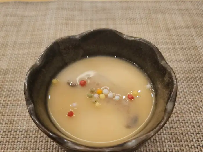 맑은 국물 위에 알록달록한 구슬 모양의 장식이 올라간 맑은 조개탕