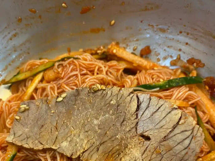 비빔냉면에 고기 편육이 올라간 모습