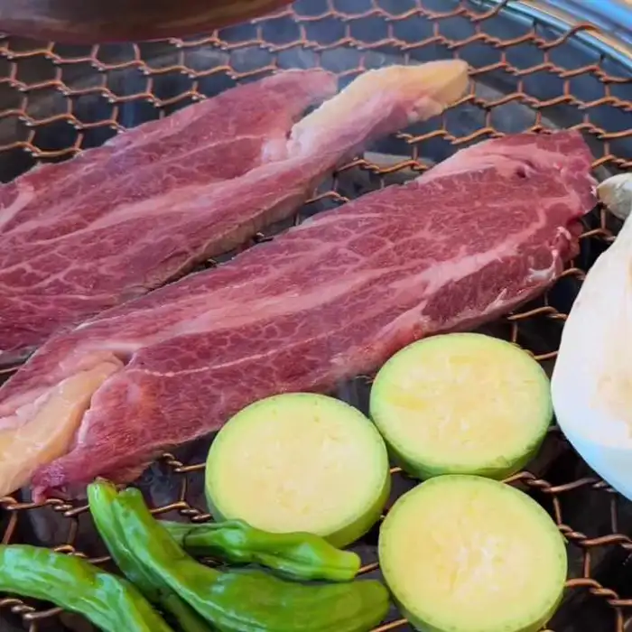 숯불 위에 올라간 신선한 한우 등심과 야채