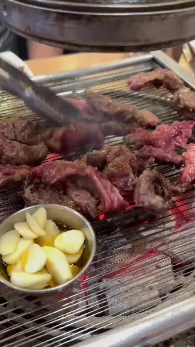 집게로 고기를 뒤집으며 굽는 모습