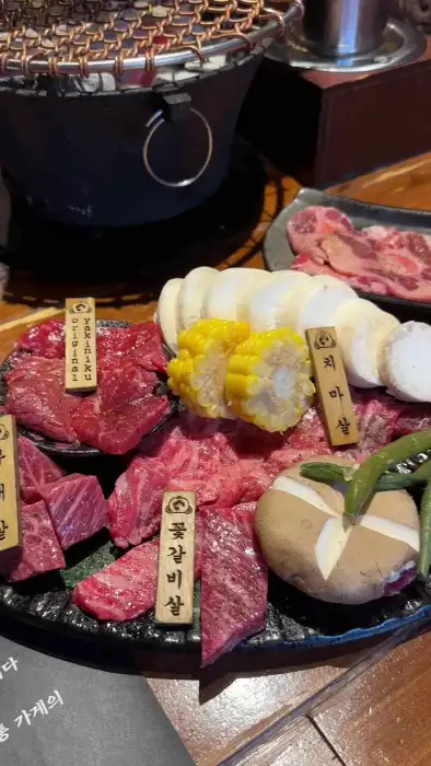 개별 화로 위에 놓인 신선한 소고기, 버섯, 옥수수, 고추 등