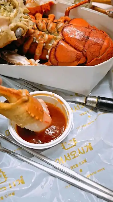 집게로 킹크랩 살을 발라 소스에 찍어 먹는 모습