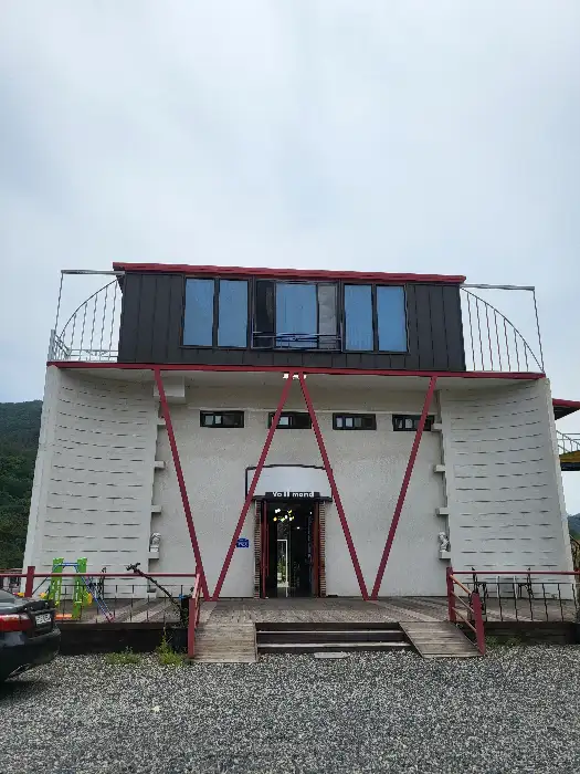 카페 건물의 외관. 현대적인 건축 양식에 큰 창문과 독특한 'W'자 모양의 입구가 특징입니다.