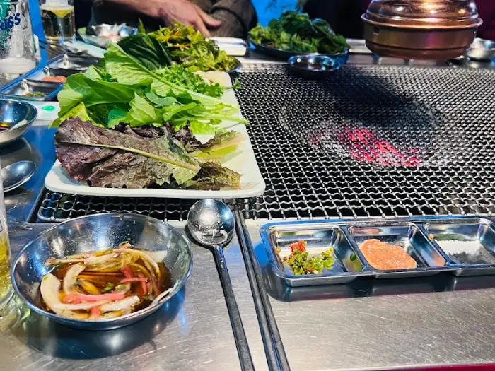 불판과 함께 놓인 신선한 쌈 채소와 소스
