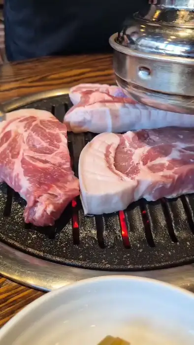 직원이 흑돼지 목살을 집게로 뒤집고 있는 모습