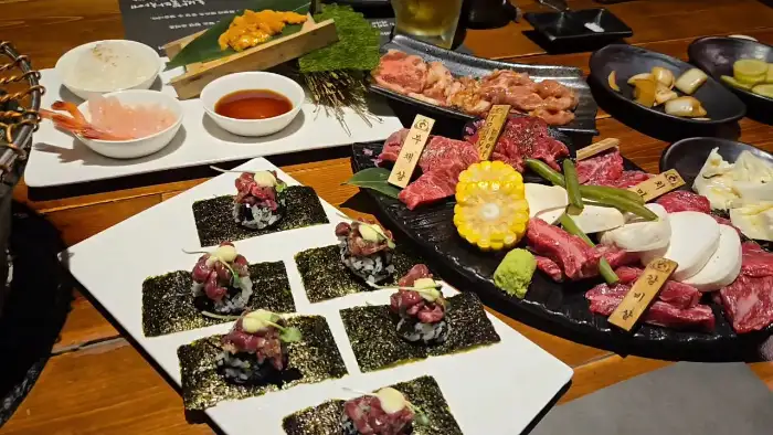 테이블 위에 차려진 다양한 음식들, 고기, 김쌈, 밥, 소스 등