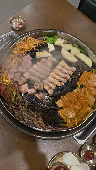 솥뚜껑 위에서 다양한 재료와 함께 익어가는 고기
