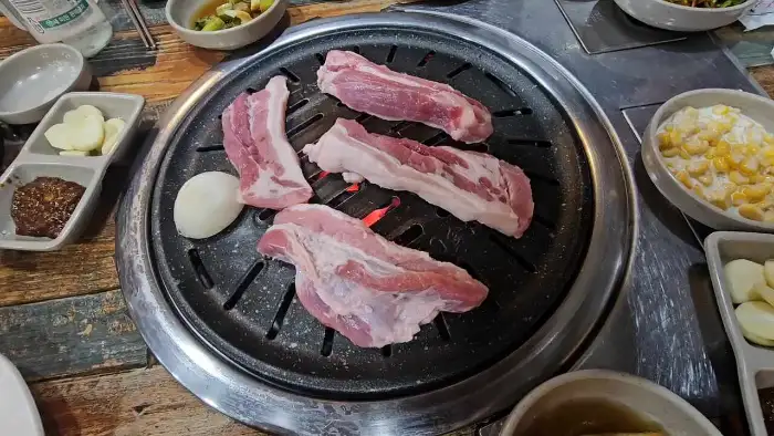 숯불 위에서 구워지는 흑돼지와 곁들임 채소