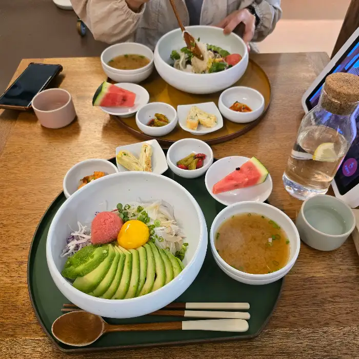 먹음직스럽게 플레이팅된 아보카도 명란 비빔밥과 곁들임