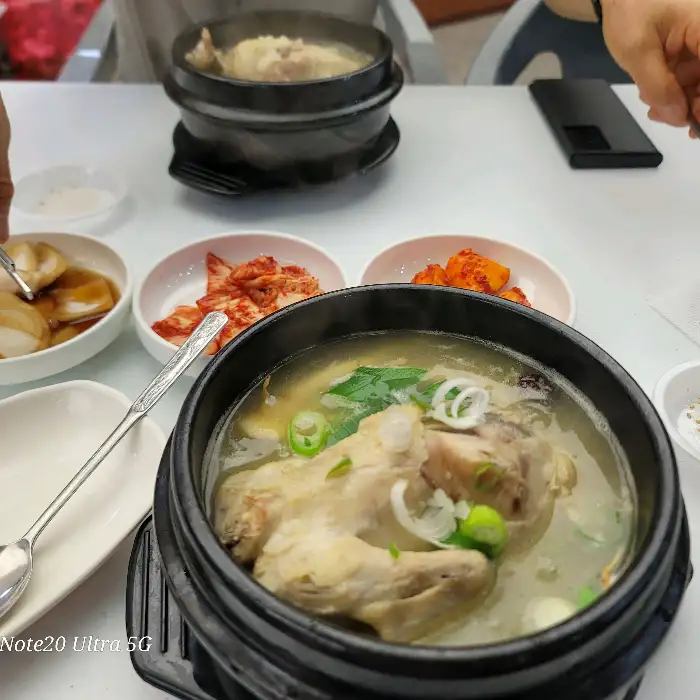 테이블에 놓인 두 그릇의 삼계탕과 여러 반찬