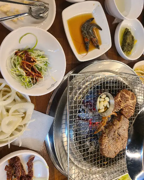 테이블 위에 세팅된 다양한 밑반찬과 숯불 구이