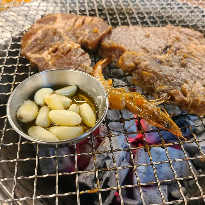 숯불 위에 익고 있는 고기와 마늘, 새우