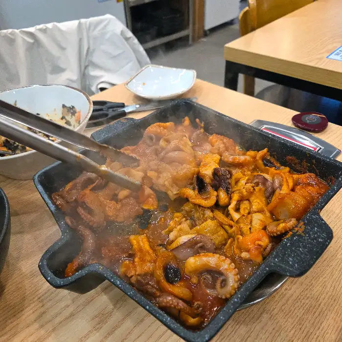 집게로 쭈꾸미와 삼겹살을 집고 있는 모습