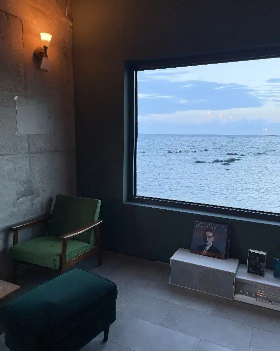 창가 옆에 놓인 초록색 암체어와 바다가 보이는 창문