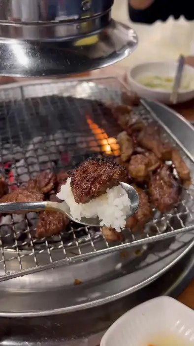 숯불 위에서 익어가는 돼지갈비와 밥 한 숟갈