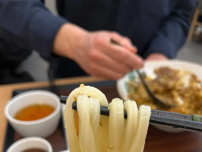 젓가락으로 집어 올린 우동 면발의 쫄깃한 식감