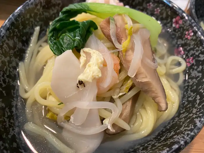 국물과 함께 나온 면 요리. 면 위에 버섯, 채소, 해산물이 올라가 있다.