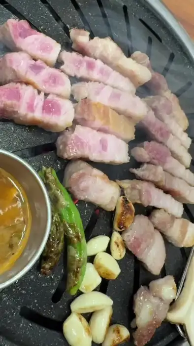 불판 위에서 구워지고 있는 삼겹살, 마늘, 꽈리고추